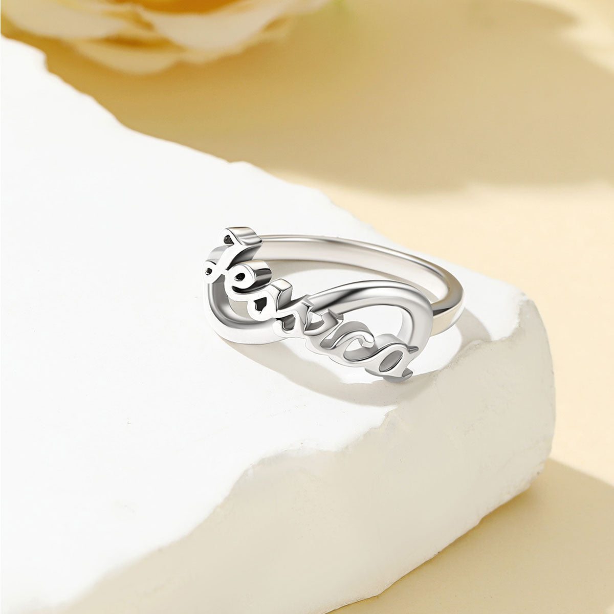 Custom Name Infinity Promise Ring for Women on white stone on a light yellow backgound