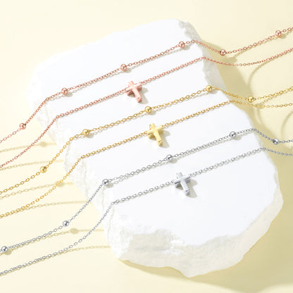 Different color of layered cross necklace on a white stone surface