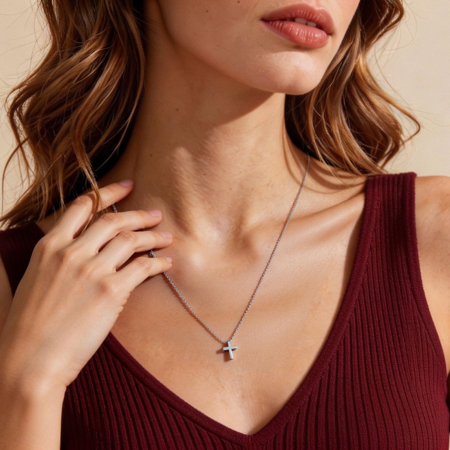 Woman wearing a maroon top and a necklace with a cross pendant.