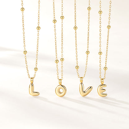 Four gold initial necklaces with bead chains and lowercase letter pendants spelling LOVE, arranged vertically on a clean white background.