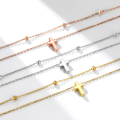 Four necklaces with cross pendants in rose gold, silver, and gold on a light background