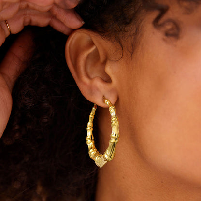 Gold Chunky hoop earrings being worn on an ear with a blurred background