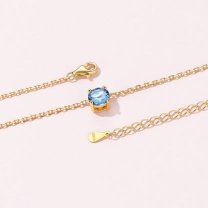 Gold Plated Solitaire Birthstone March Necklace on a pink background
