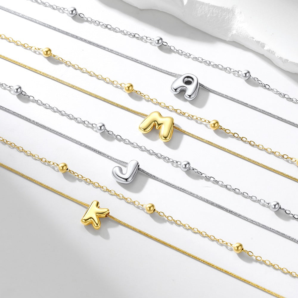 Gold and silver initial necklaces with letter pendants on a white background