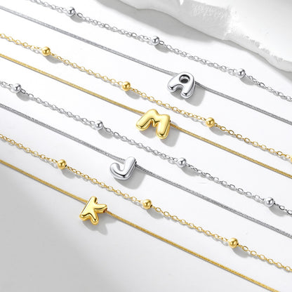 Gold and silver initial necklaces with letter pendants on a white background