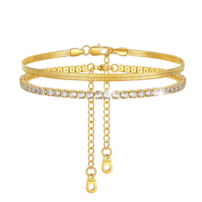 Gold anklet bracelet with chain and clear stones on a white background