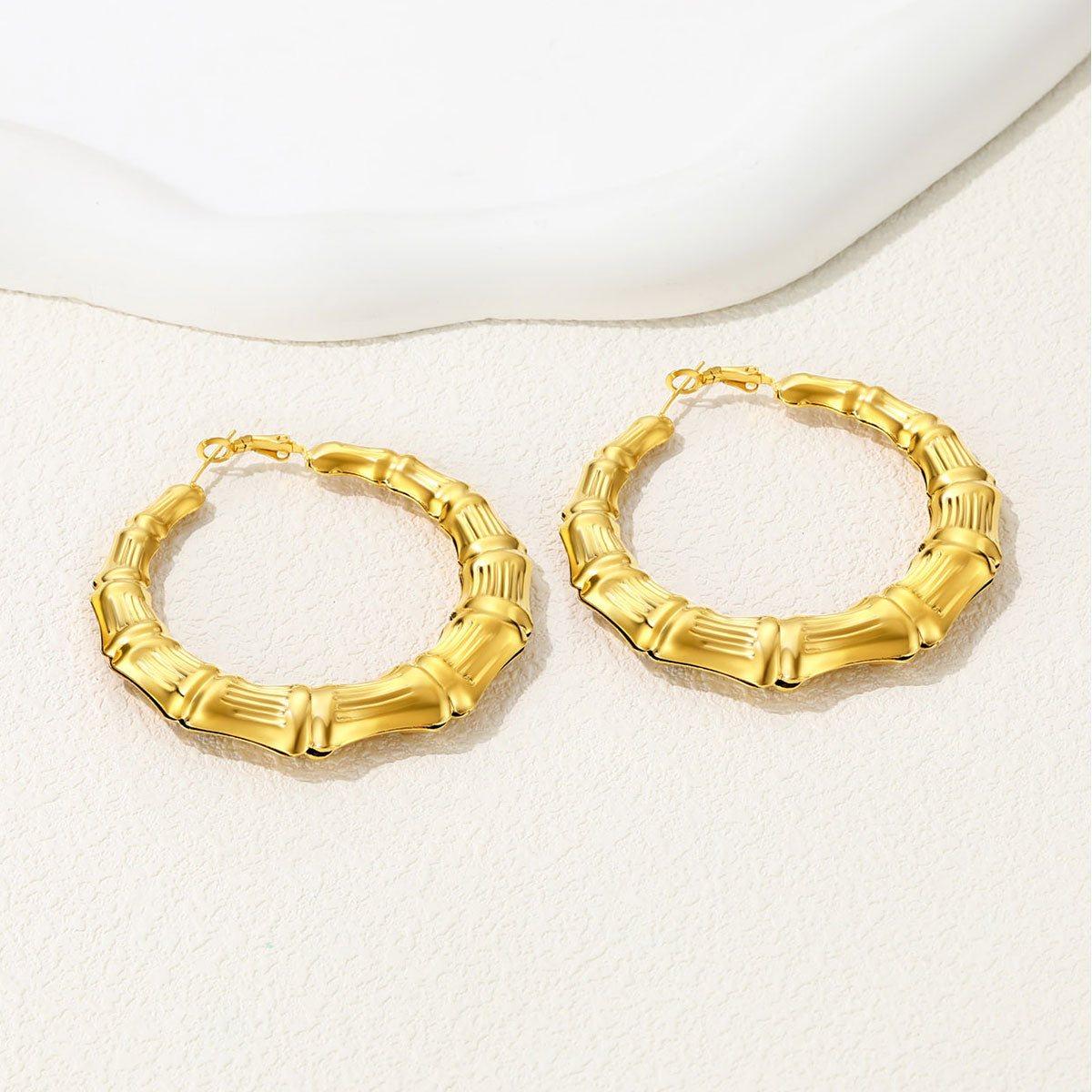 Gold bamboo hoop earrings on a white background