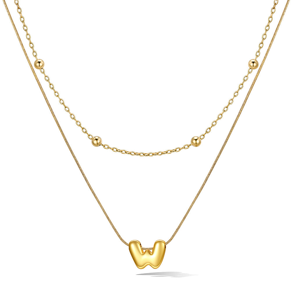 Gold bubble initial necklace with a unique pendant on a white background