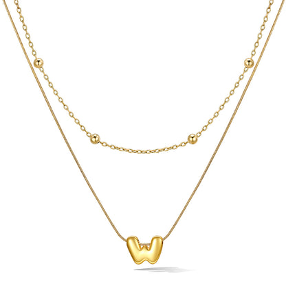 Gold bubble initial necklace with a unique pendant on a white background
