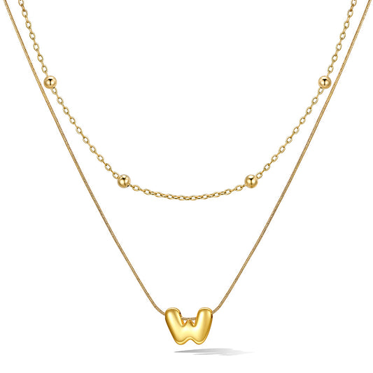 Gold bubble initial necklace with a unique pendant on a white background