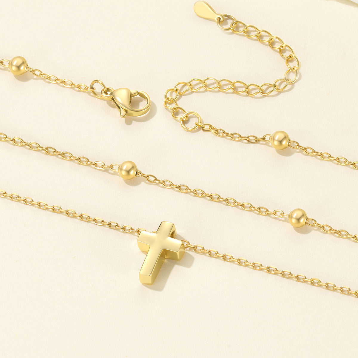 Gold cross necklace with a cross pendant on a light beige background