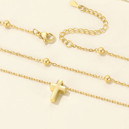 Gold cross necklace with a cross pendant on a light beige background