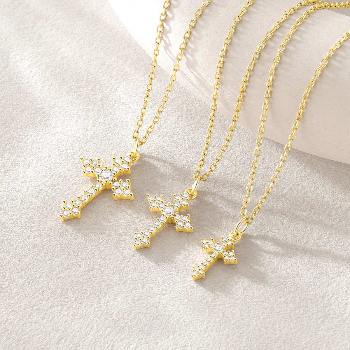 Gold cross necklaces with clear stones on a light background
