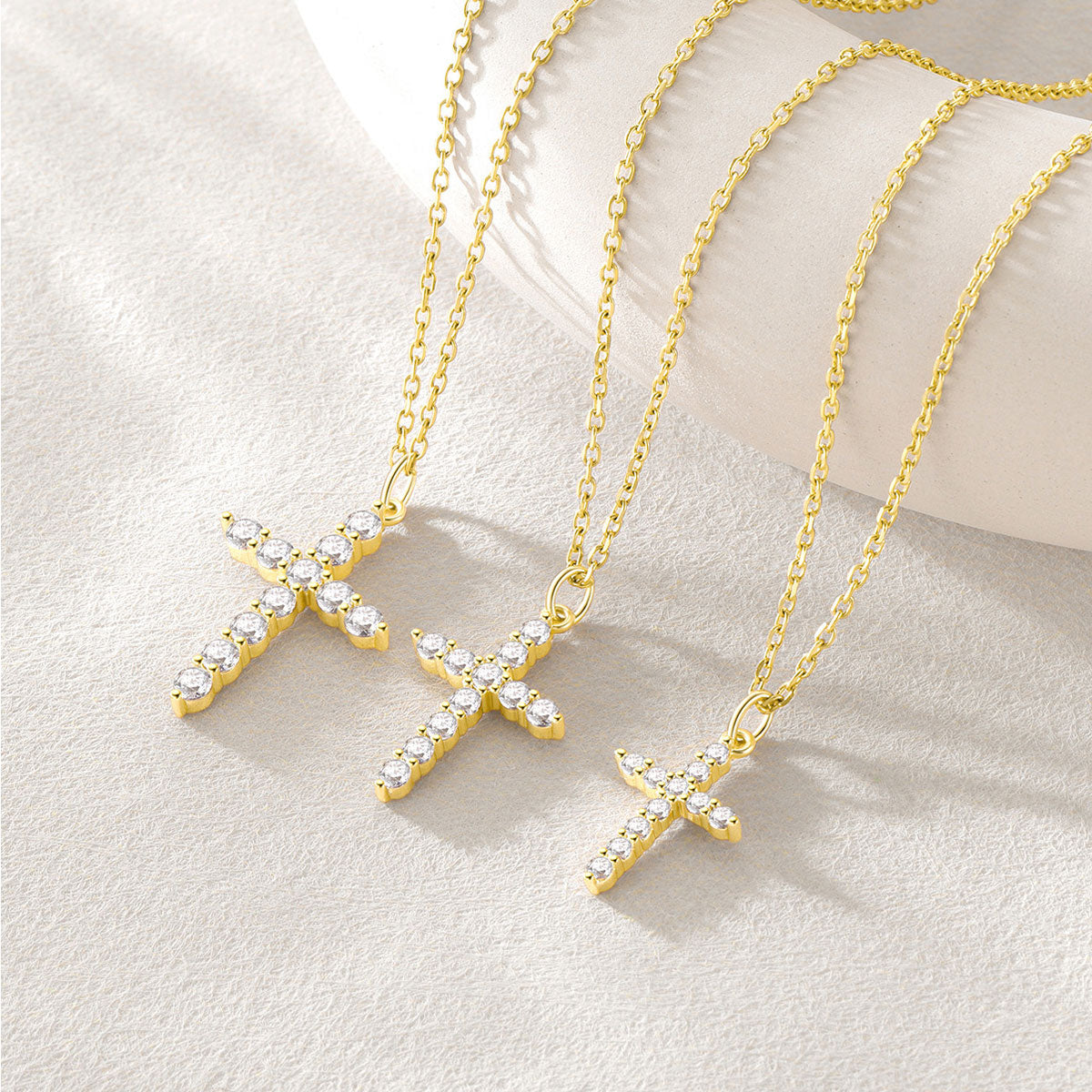 Gold cross necklaces with clear stones on a light background