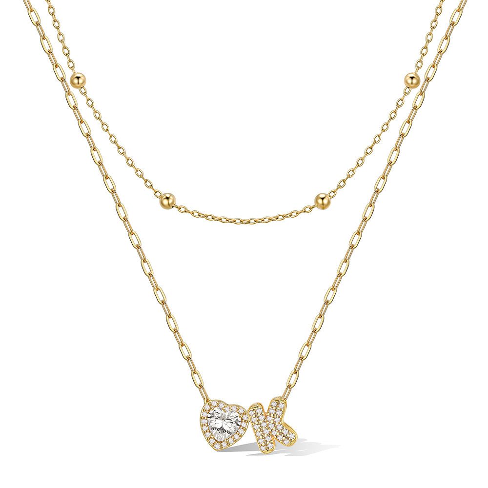Gold cz bubble initial K necklace with a heart-shaped pendant on a white background