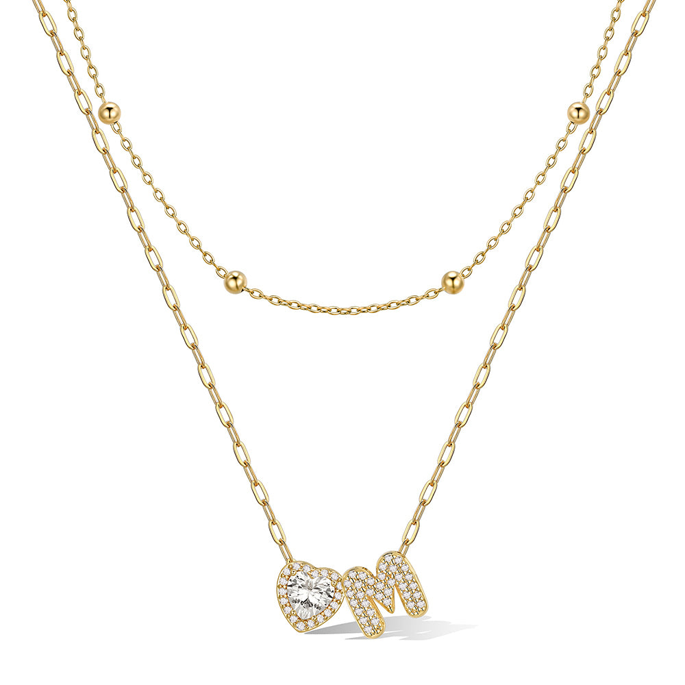 Gold cz bubble initial M necklace with a heart-shaped pendant on a white background