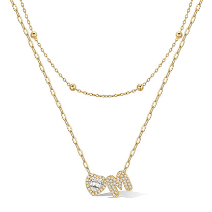 Gold cz bubble initial M necklace with a heart-shaped pendant on a white background