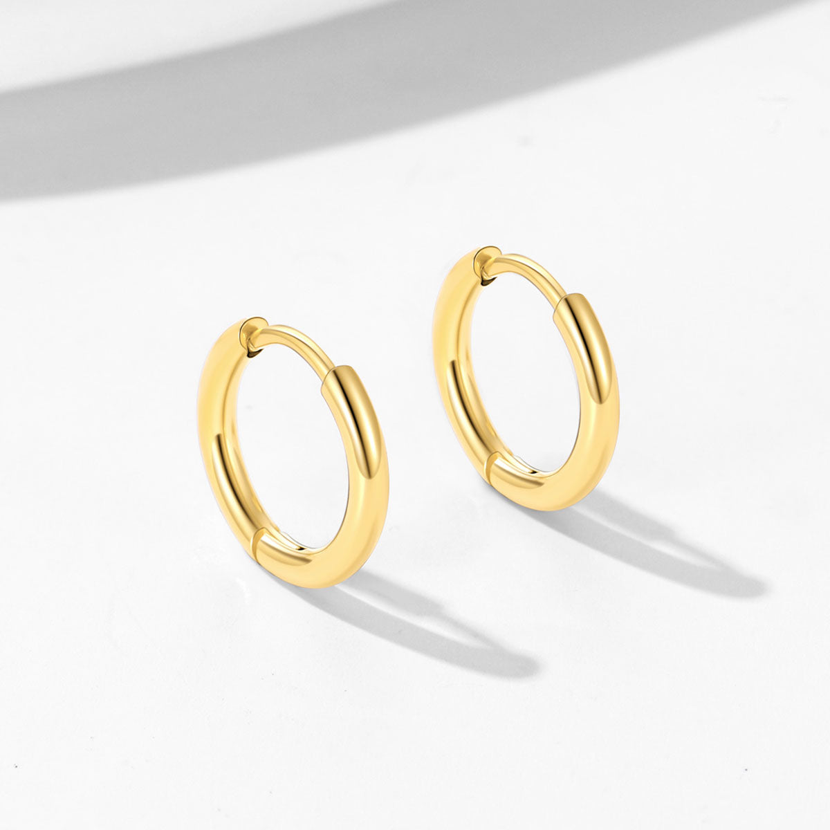 Gold huggie earrings on a light gray background