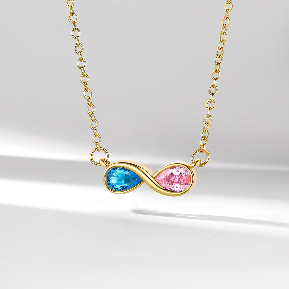 Gold infinity necklace with blue and pink gemstones on a light gray background