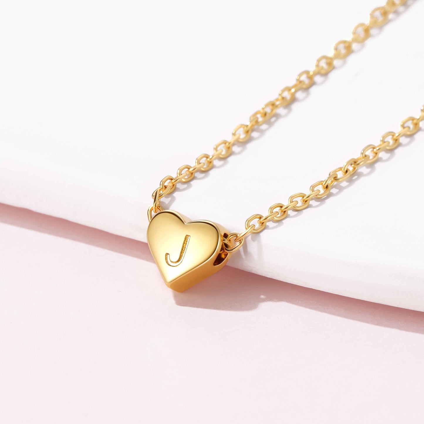 Gold initial heart necklace with a heart-shaped pendant featuring an initial on a white background