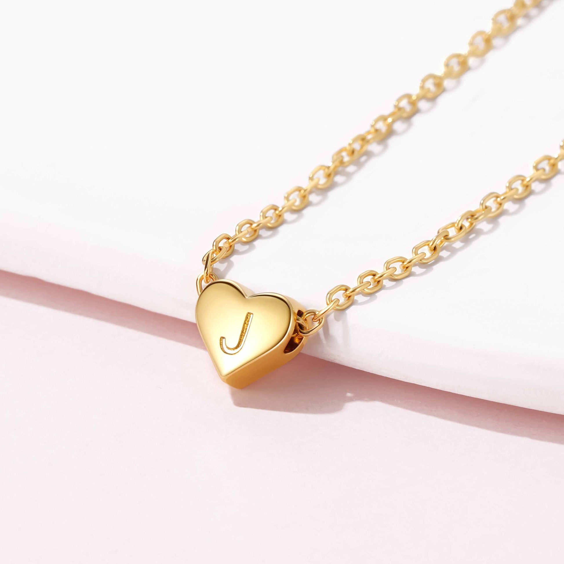 Gold initial heart necklace with a heart-shaped pendant featuring an initial on a white background