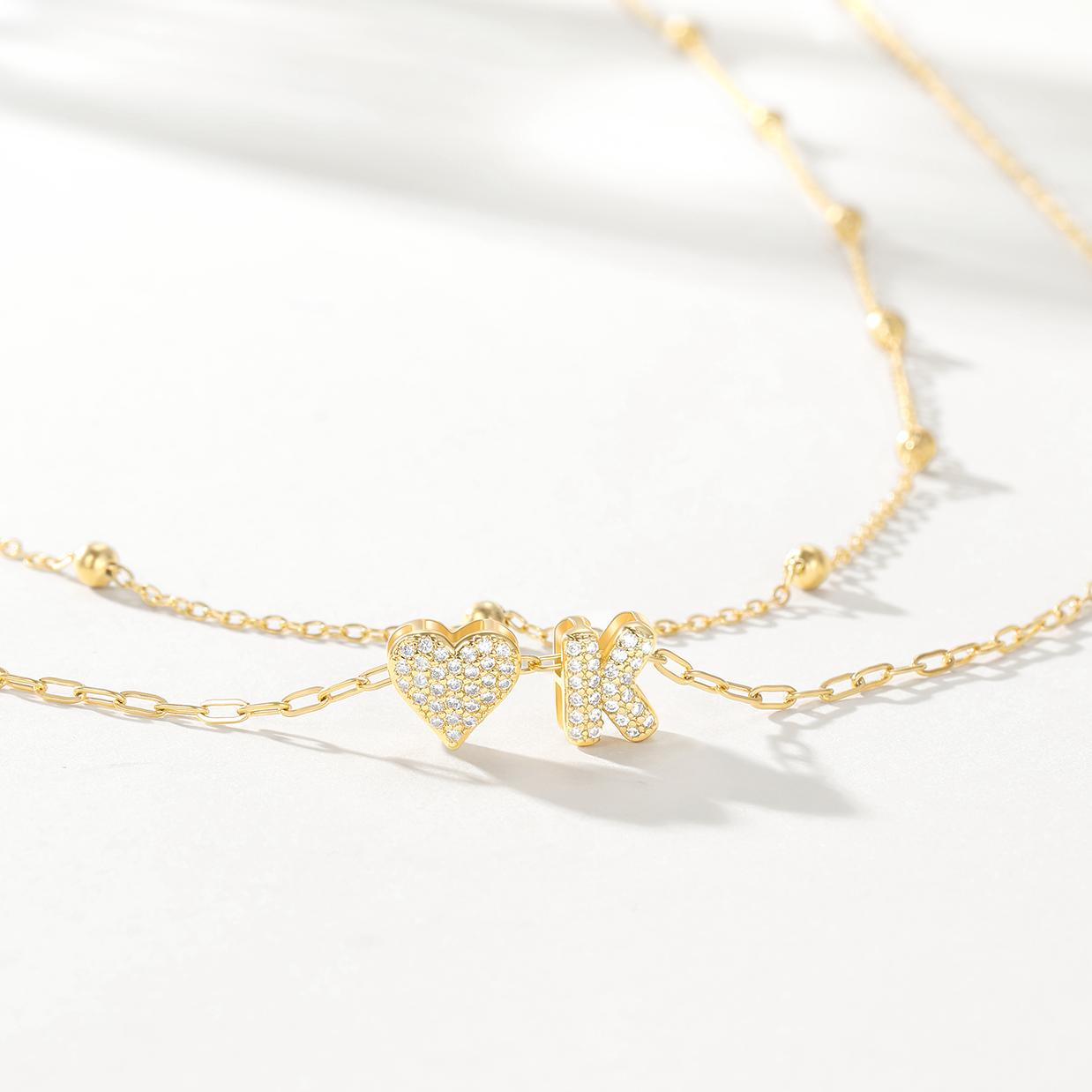 Gold initial necklace with a bow-shaped pendant on a white background