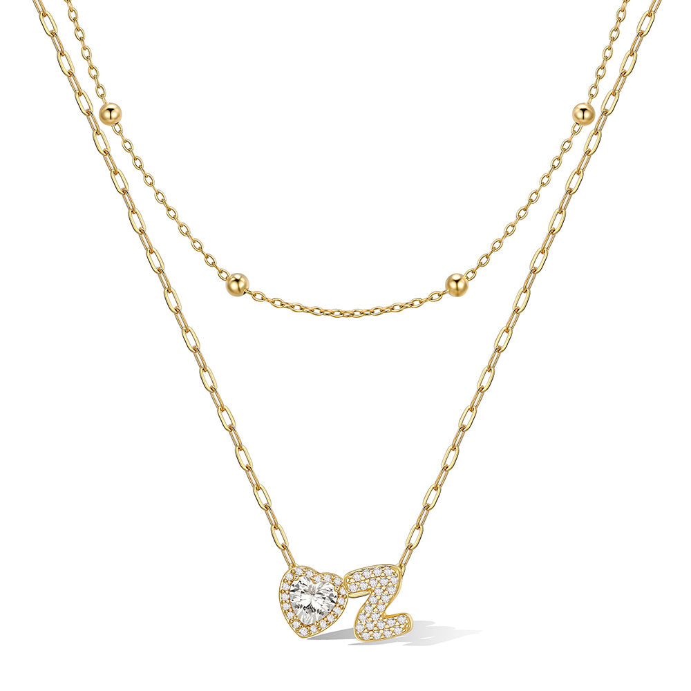 Gold initial necklace with a heart-shaped pendant on a white background