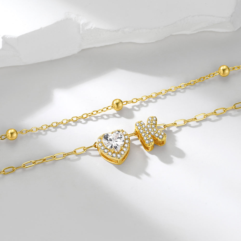 Gold initial necklace with heart-shaped clasp and diamond on a white background