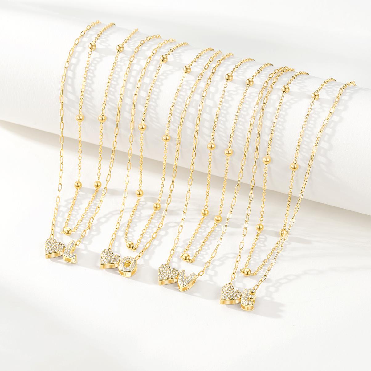 Gold initial necklaces with heart-shaped pendants on a white background