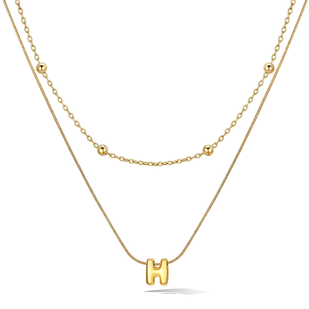 Gold layered initial H necklace, showing measurements and material details.