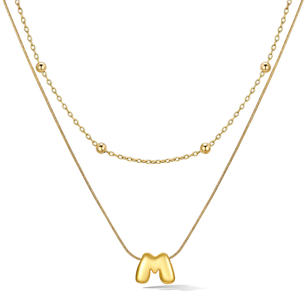 Gold layered initial M necklace with letter 'M' pendant, showing measurements and material details.