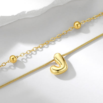 Gold layered initial necklace with a unique clasp on a light gray background