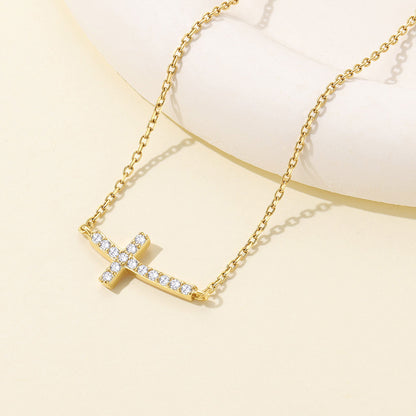 Gold plated Dainty Cubic Zirconia Sideways Cross Necklace for Women on a light yellow background