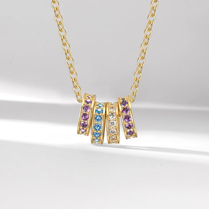 Gold stacking birthstone necklace with colorful gemstones on a light gray background