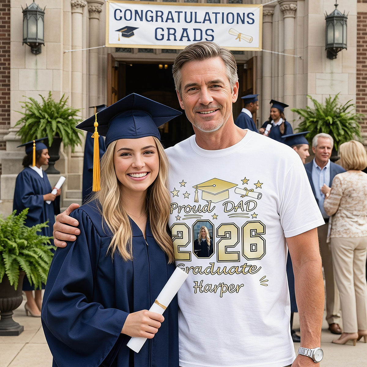 Graduating student in cap and gown with father wearing a 'Proud Dad 2026 Graduate' t shirt, celebrating graduation.