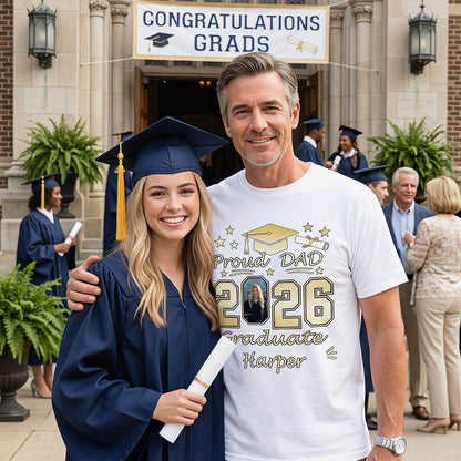 Graduating student in cap and gown with father wearing a 'Proud Dad 2026 Graduate' t shirt, celebrating graduation.