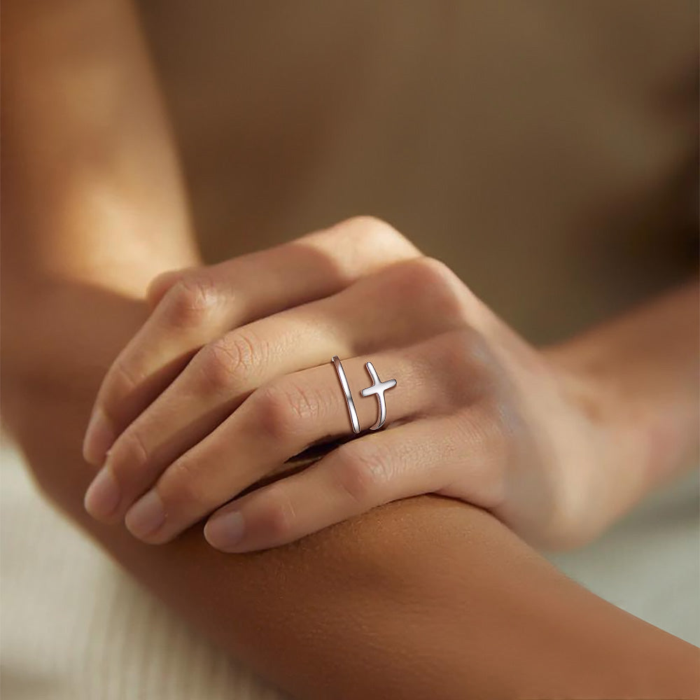 Hand wearing a silver cross ring on a blurred background