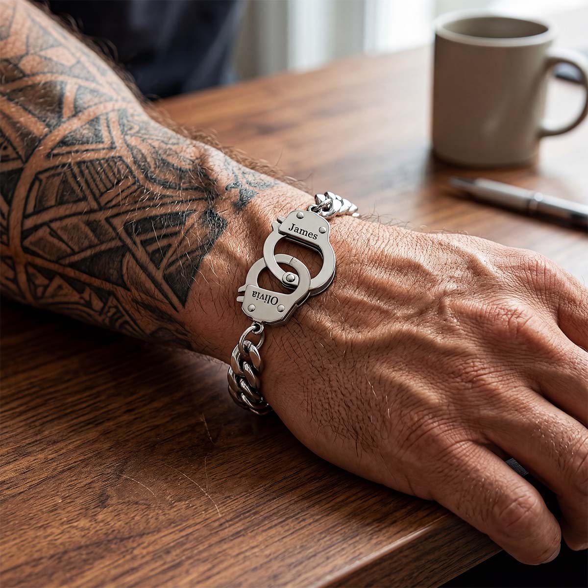 Hand wearing a silver custom handcuff bracelet with a unique design on a wooden surface.