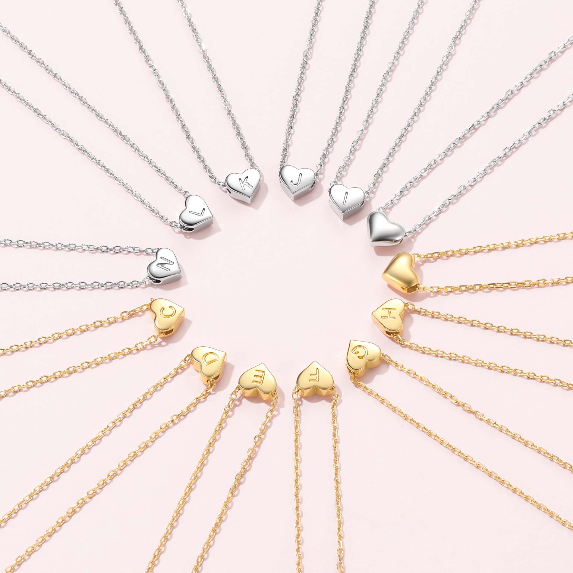 Heart initial Necklaces in silver and gold on a pink background