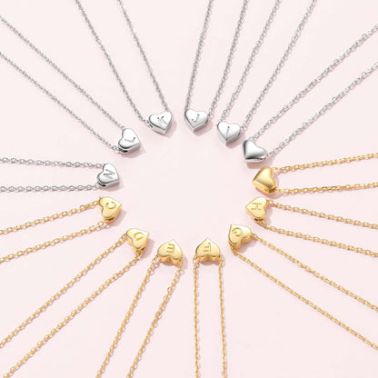 Heart initial Necklaces in silver and gold on a pink background