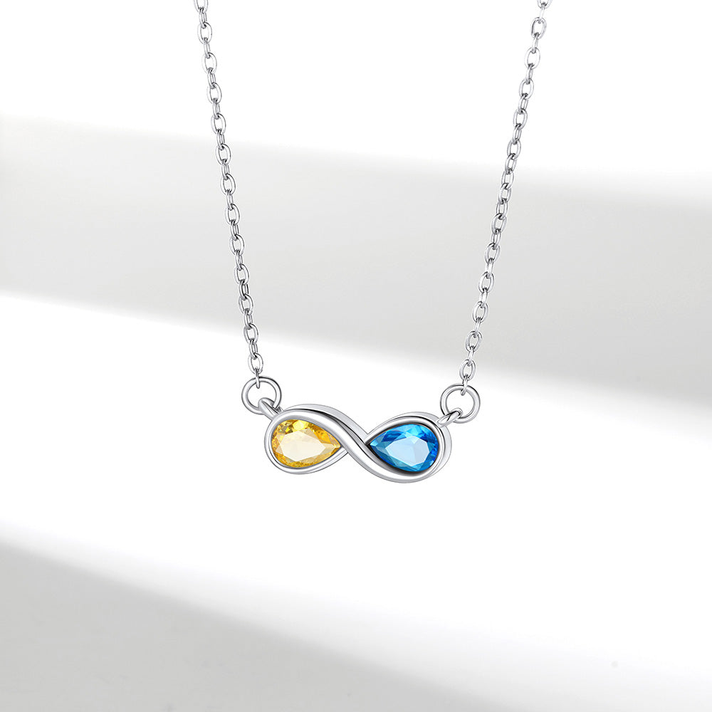 Infinity birthstone necklace with yellow and blue gemstones on a white background