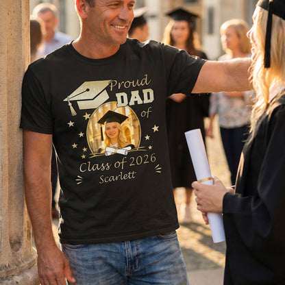 Man wearing a 'Proud Dad of Class of 2026' custom photo graduation t-shirt with a photo of a graduate, standing outdoors with people in the background.