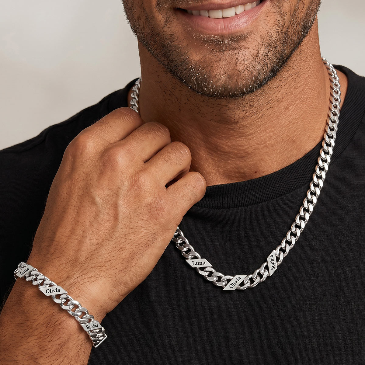 Man wearing a silver chain necklace and bracelet on a plain background