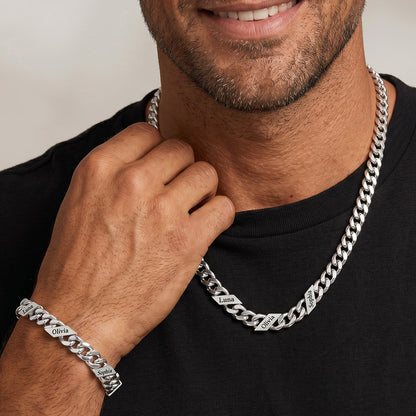 Man wearing a silver chain necklace and bracelet on a plain background