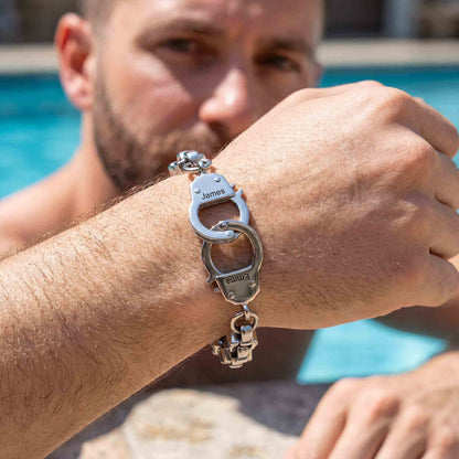 Man wearing a silver custom handcuff bracelet by a pool