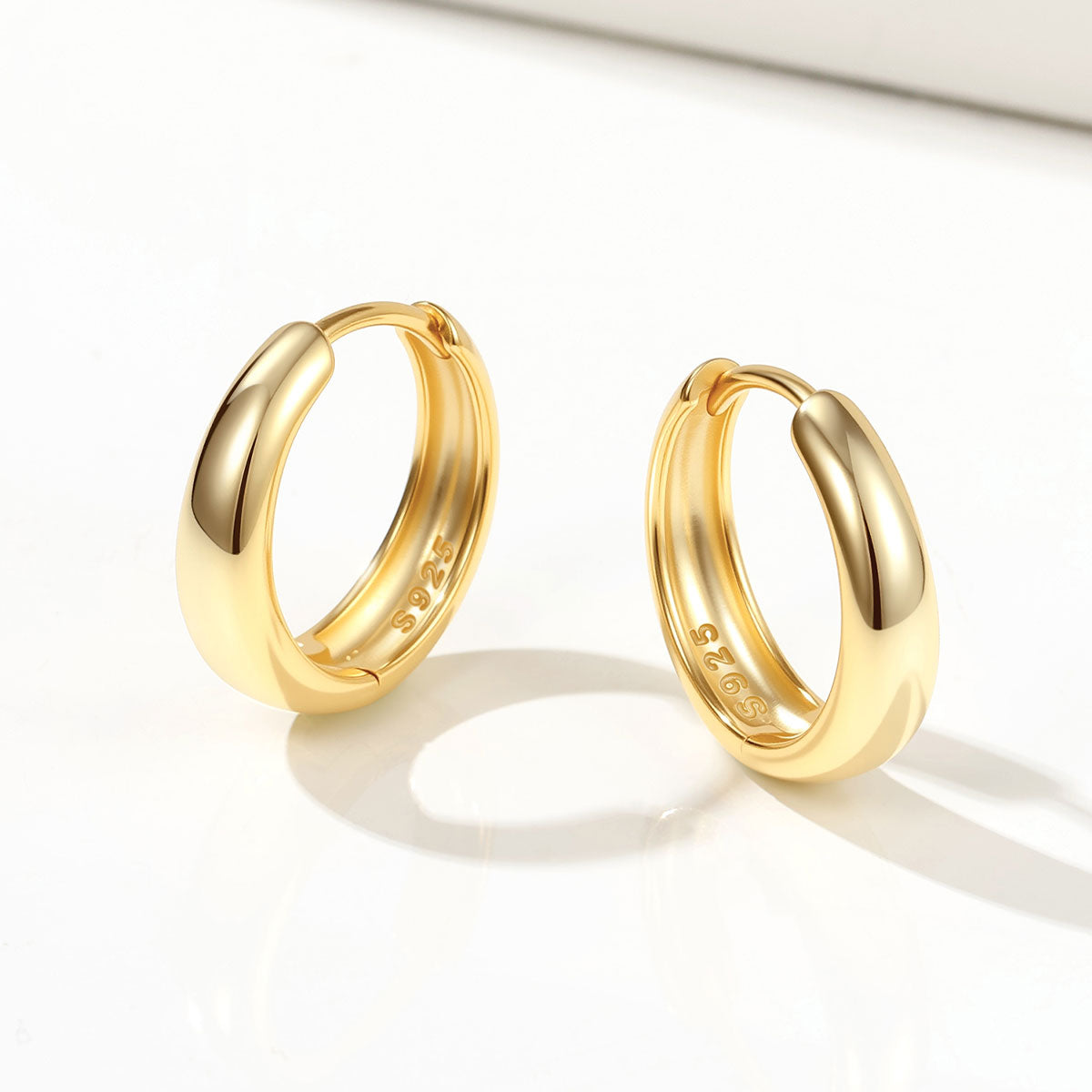Pair of gold huggie earrings on a white background