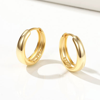 Pair of gold huggie earrings on a white background