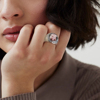Person wearing a picture signet ring with a photo on it, close-up of hand and face.