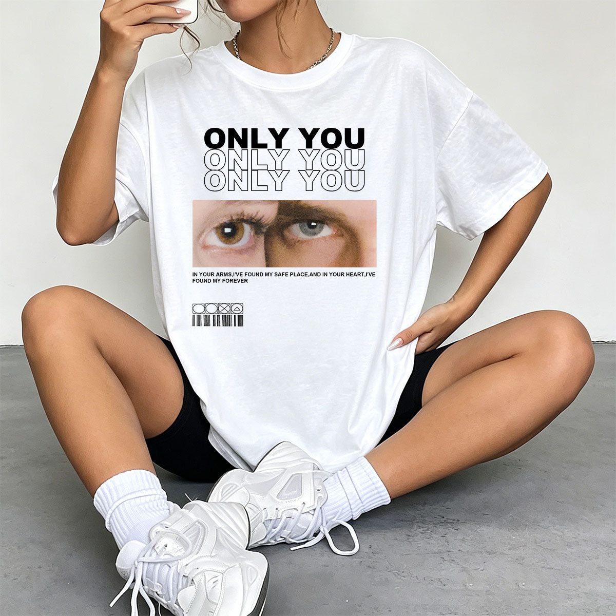 Person wearing a white custom eye photo t-shirt with a graphic and text, sitting on the floor.