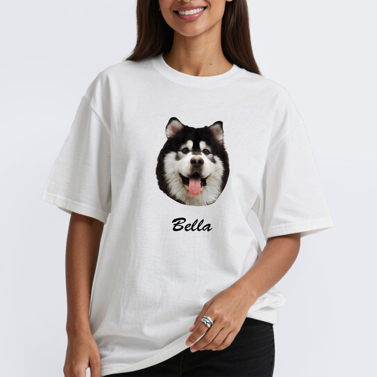 Person wearing a white custom pet t-shirt with a dog's face and name 'Bella' on a plain background